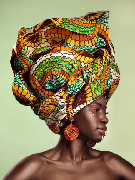 Studio shot of a beautiful young woman wearing a traditional African head wrap against a green background