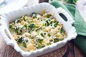 Baked broccoli with chicken in a ceramic form on a wooden table, selective focus