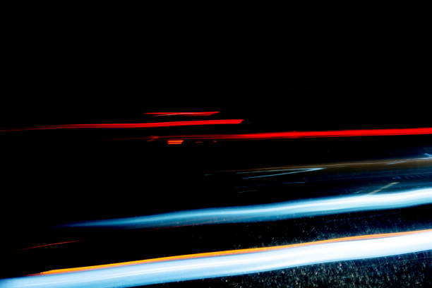 Light trails from cars passing through a dark tunnel on a rainy night