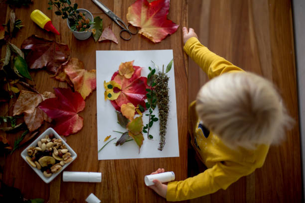 istock Sweet child, toddler boy, applying leaves using glue 1186707467