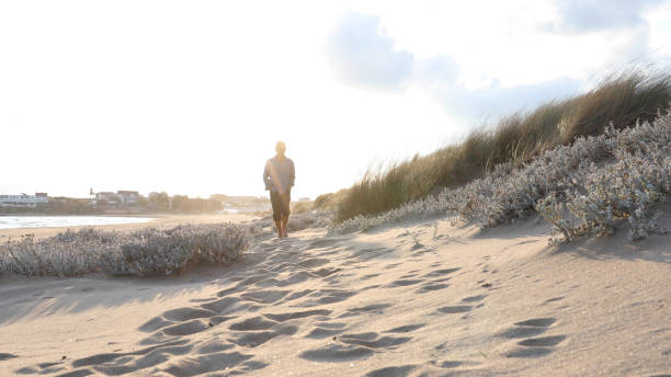 istock Mature man walks along beach at sunrise 1186709340