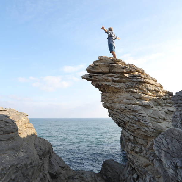 istock Mature man scrambles along coastal cliffs at sunrise 1186711822
