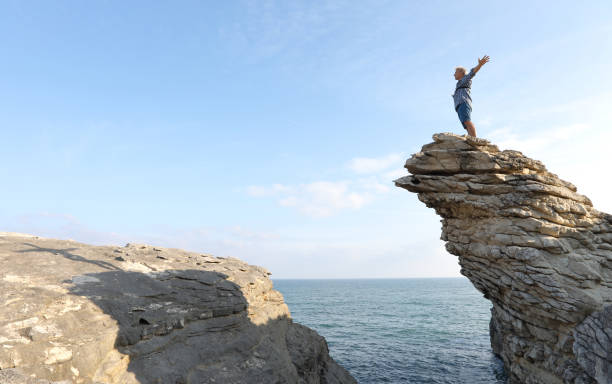 istock Mature man scrambles along coastal cliffs at sunrise 1186711946