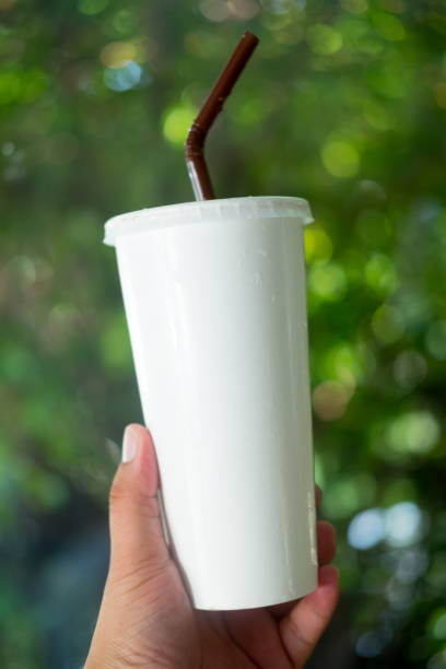 istock White paper cup with drinking straw in hand on nature background 1186712012