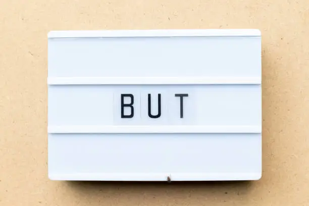 White lightbox with word but on wood background
