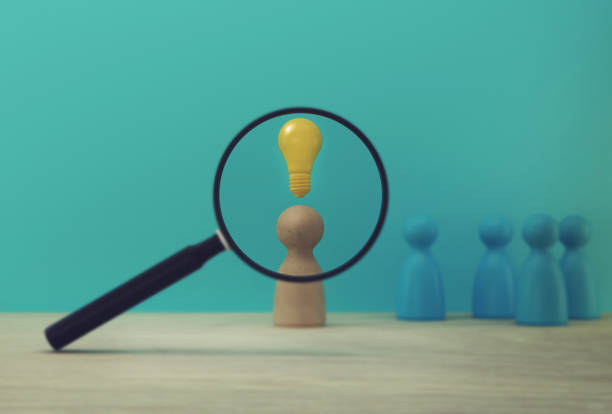 istock Magnifying glass with people model and light bulb icon outstanding out from the crowd. Human resource and talent management and business building team of employee in organization 1186720797