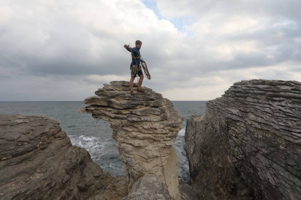 istock Young man throws rock from coastal rock feature at sunrise 1186726273