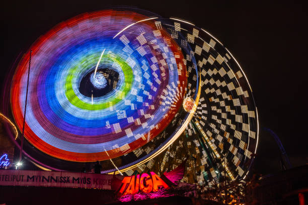 l'evento carnival of light al parco divertimenti linnanmaki. guida la ruota panoramica rinkeli e kehra in movimento, illuminazione notturna, lunga esposizione. - ferris wheel wheel blurred motion amusement park foto e immagini stock