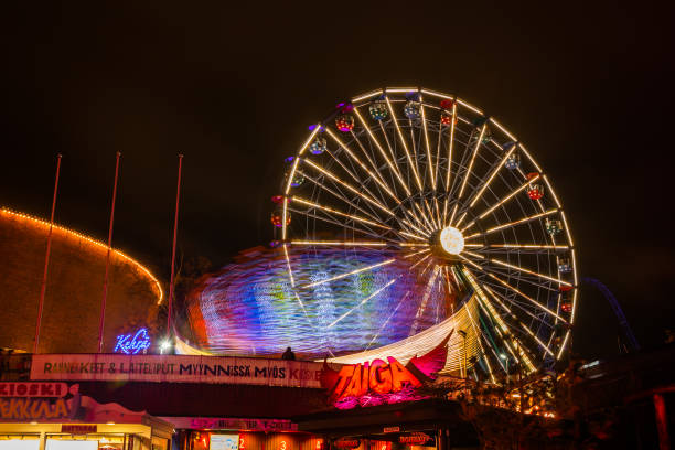 l'evento carnival of light al parco divertimenti linnanmaki. guida la ruota panoramica rinkeli e kehra in movimento, illuminazione notturna, lunga esposizione. - ferris wheel wheel blurred motion amusement park foto e immagini stock