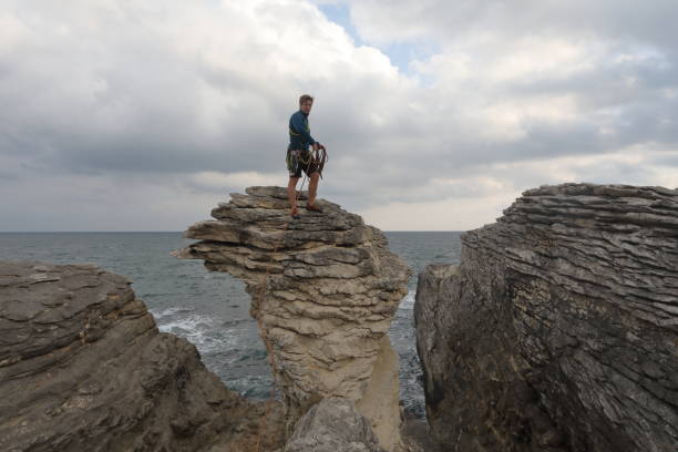 istock Young man throws rock from coastal rock feature at sunrise 1186726717