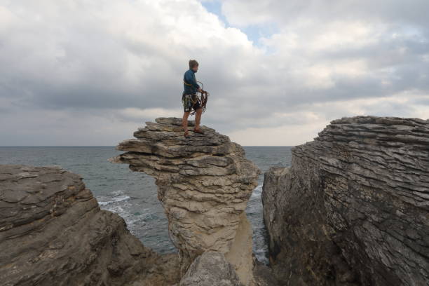 istock Young man throws rock from coastal rock feature at sunrise 1186727621