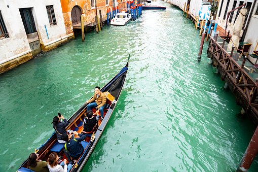 Venice canal with a close-up of a gondola taking tourists on a guided trip around the canals in the rain.