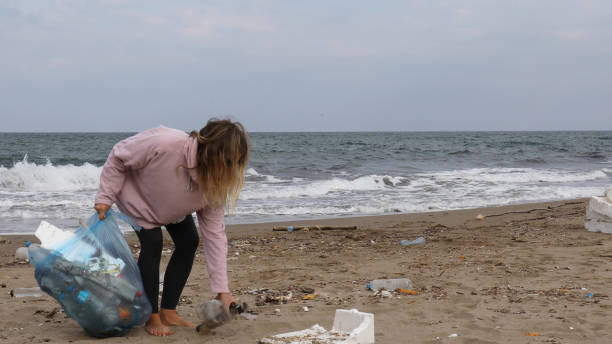 istock Young woman pick up garbage on beach 1186731068