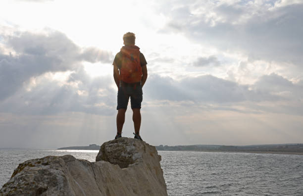 istock Hiker balances on coastal cliff over the sea 1186731087