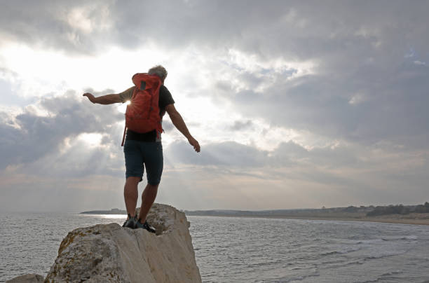 istock Hiker balances on coastal cliff over the sea 1186731273