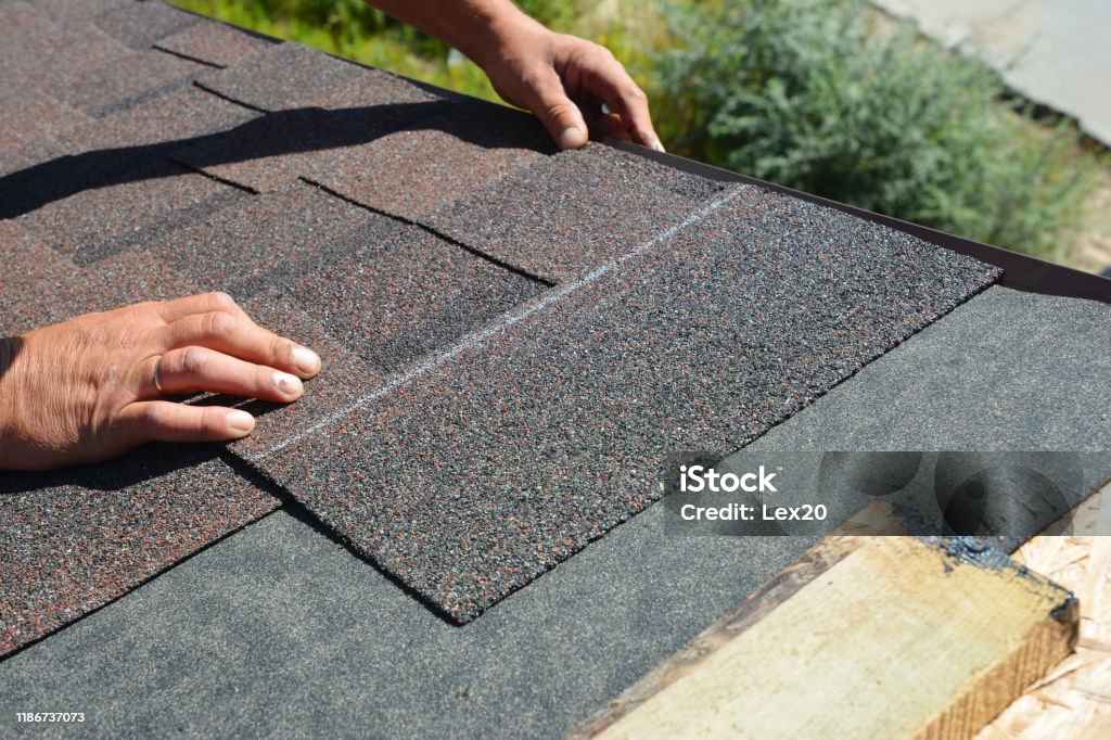 Installation av asfalt bältros. Roofer entreprenör installera asfalt bältros på hus tak konstruktion - Royaltyfri Takläggare Bildbanksbilder