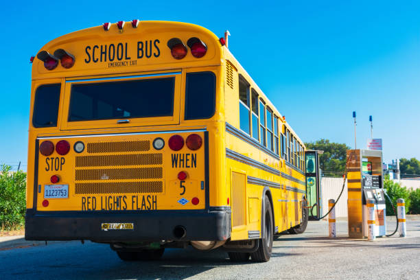 Yellow low emissions school bus refuel cleanest burning alternative fuel at compressed natural gas CNG fueling station owned by PG&E San Carlos, CA, USA - 2019 : Yellow low emissions NGV school bus refuel cleanest burning alternative fuel at compressed natural gas CNG fueling station owned by PG&E school bus stock pictures, royalty-free photos & images