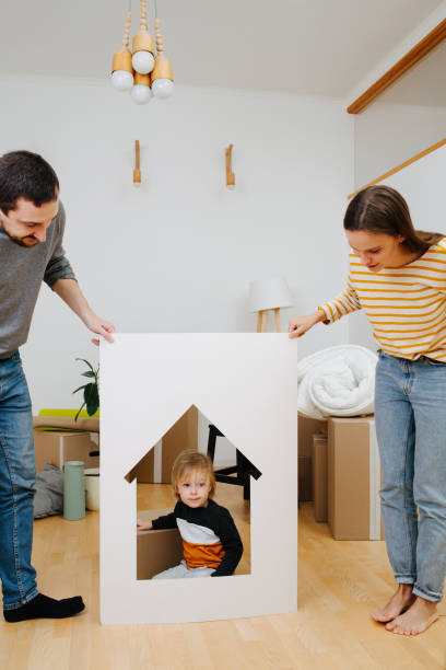 istock Little boy sitting inside a house resembling frame, held by his parents 1186745540
