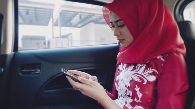 Businesswoman working at smartphone in back seat of crowdsourced taxi.