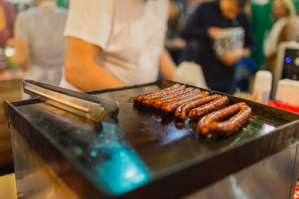 Close up image of sausages cooking on a flat grill. Street food concept.