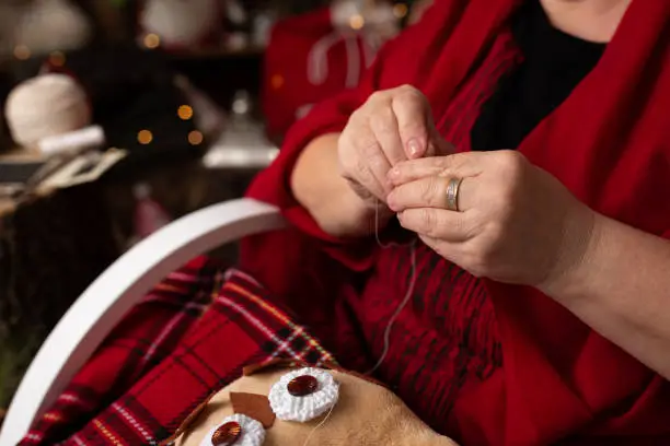 Photo of Grandmother sews a plush owl in Christmas arrangement