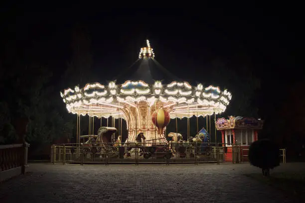 Photo of Old fashioned carousel backlit in a night park. Kharkov, Gorky Park.