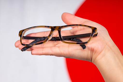 Close up of a female hand holding a pair of glasses with a japan flag