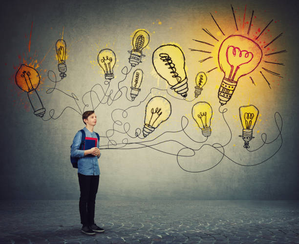 istock Student boy holding books and backpack imagining bright lightbulbs on the wall. Smart and ingenious teen guy has different thinking, genius creativity concept, alternative idea as the way to success. 1186772496