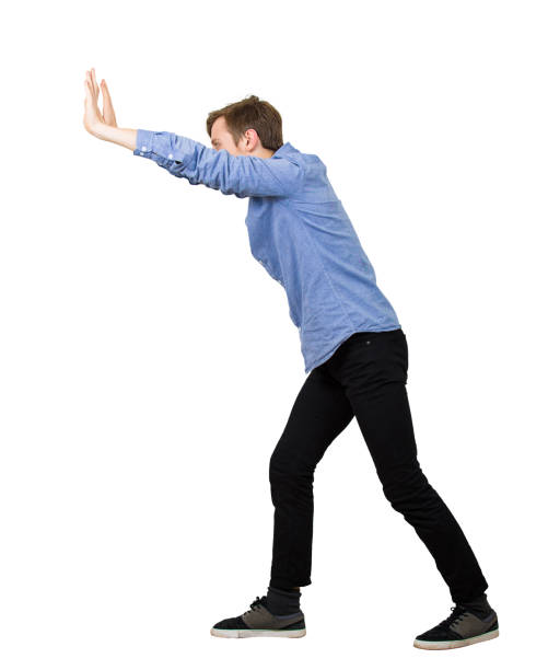 istock Determined teenage guy making effort as pushing an heavy invisible object isolated on white background. Confident boy, difficult task concept, convinced in his powers, finding solutions to problems. 1186772537