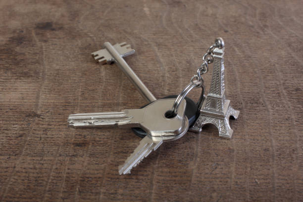 Keys to apartment with a keychain in form of an eiffel tower on a wooden table
