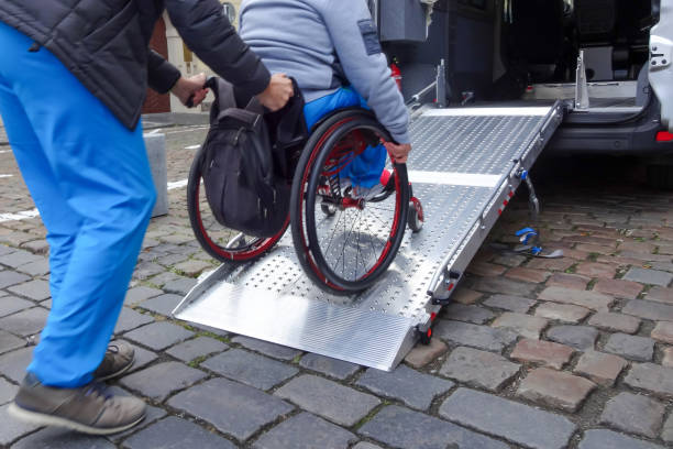 Disabled person on wheelchair using car lift Assistant helping disabled person on wheelchair with transport using accessible van ramp physical disability photos stock pictures, royalty-free photos & images