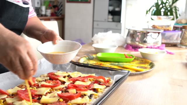 Close Hands Of Senior Woman Preparing Pizza In Kitchen