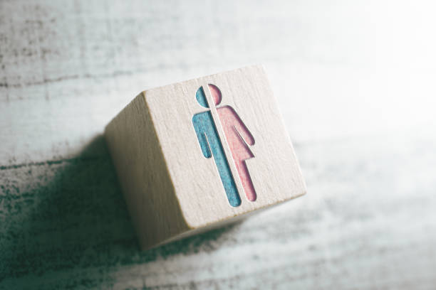 geslachts tekens voor mannelijke en vrouwelijke knippen in tweeën op een houten blok op een tafel - transgender stockfoto's en -beelden
