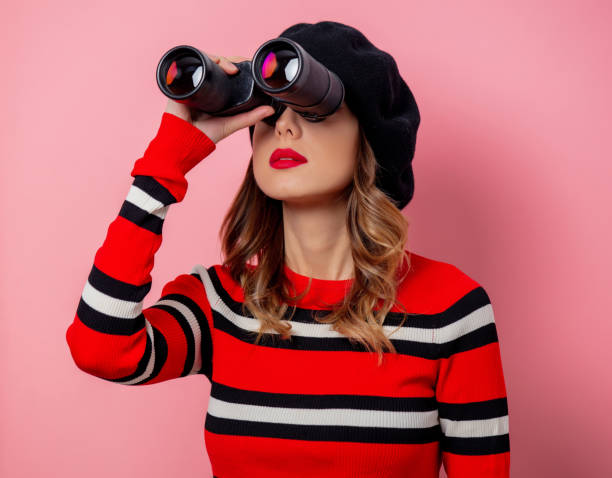 istock Young woman in sweater with binoculars on pink background 1186784955
