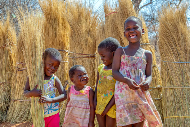少数の幸せな女の子と遊んでいる少年のグループ - africa child village smiling ストックフォトと画像