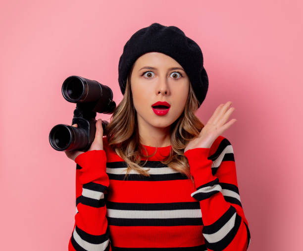 istock Young woman in sweater with binoculars on pink background 1186786871