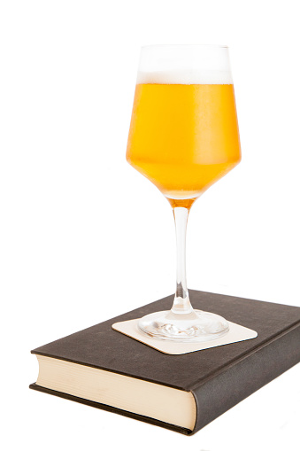 a cup of beer on a coaster on a book, isolated on white