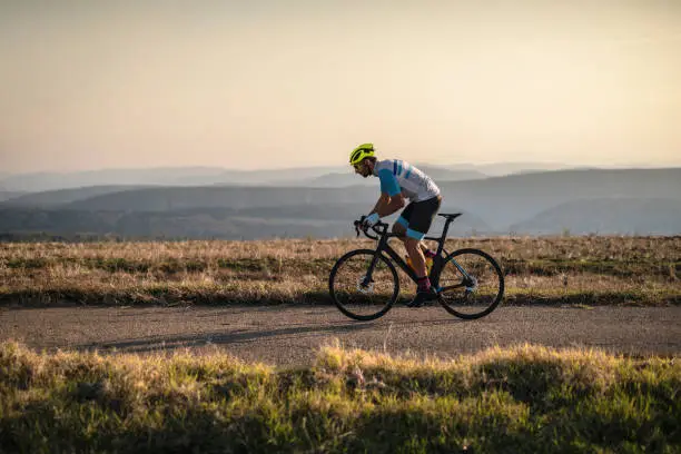 Athlete on racing bike outdoors at sunset.