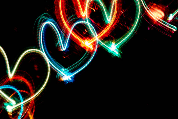 istock Diagonal row of multicolored neon glowing hearts on black background with copy space. 1186807886