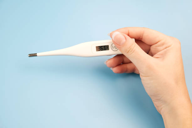 istock Female hand holding a digital thermometer on blue background. 1186808014