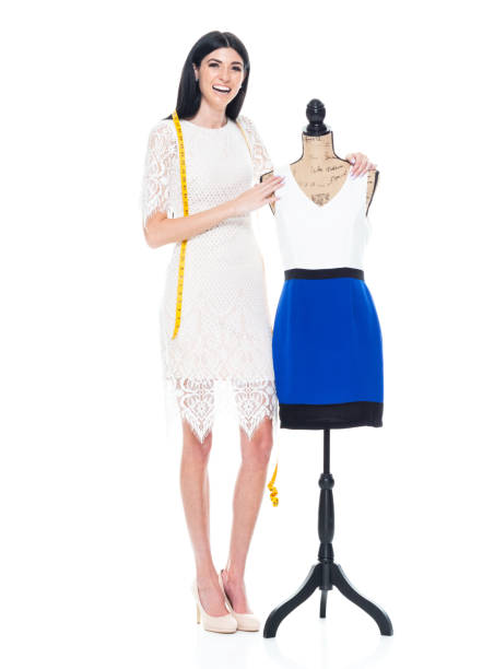 Full length / one person / front view of 20-29 years old adult beautiful / tall person / long hair caucasian young women / female tailor / owner / fashion stylist / creative occupation / craftsperson / businesswoman sewing / standing in the clothing store wearing dress who is smiling / happy / cheerful / cool attitude and using tape measure / small business longitud completa / una persona / vista frontal de 20-29 años de edad adulto hermoso / persona alta / pelo largo caucásicos mujeres jóvenes / mujer sastre / propietario / estilista de moda / ocupación creativa / artesano / mujer de negocios cosiendo /