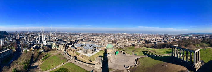 Edinburgh, Scotland, United Kingdom – February 15, 2019: Calton Hill offers premium panoramic views of landmarks in both Old Town and New Town Edinburgh and even further like the Kingdom of Fife. In the park, people walk around and explore the Calton Hill grounds.