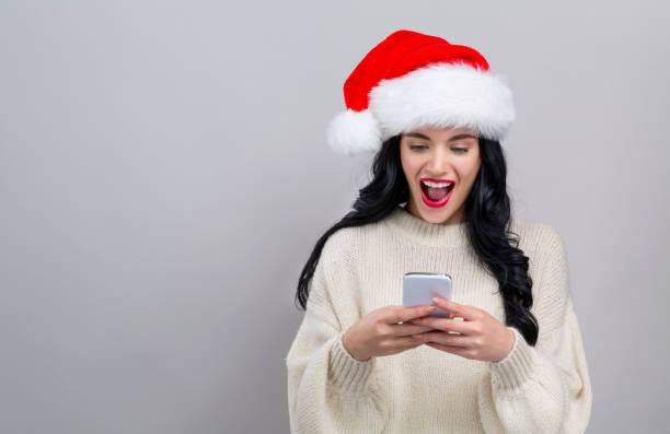 istock Young woman in a Santa hat using her smart phone 1186815461