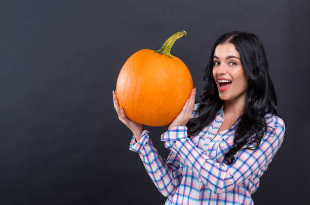 istock Young woman holding a pumpkin 1186816633