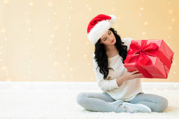 istock Young woman with santa hat holding a gift box 1186816635