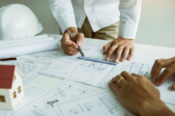 istock Architects engineer working with blueprints on table and discussing project together at the meeting in the office. 1186820941