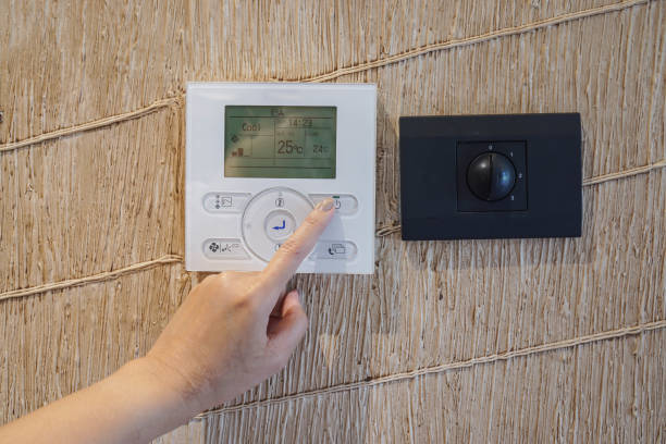 istock close up woman set bedroom temperature at wall panel at 25 Degree Celsius for saving energy 1186834270