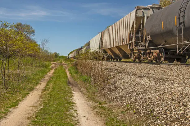 Railroad cars parked on railroad tracks next to a two-track trail for vehicles