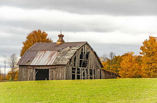 Impressive barn in need of repair on a fall day with clouds