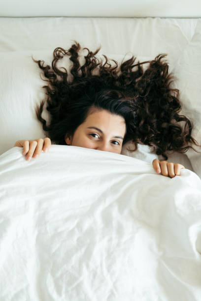 istock woman having fun in bed hiding after blanket 1186842937
